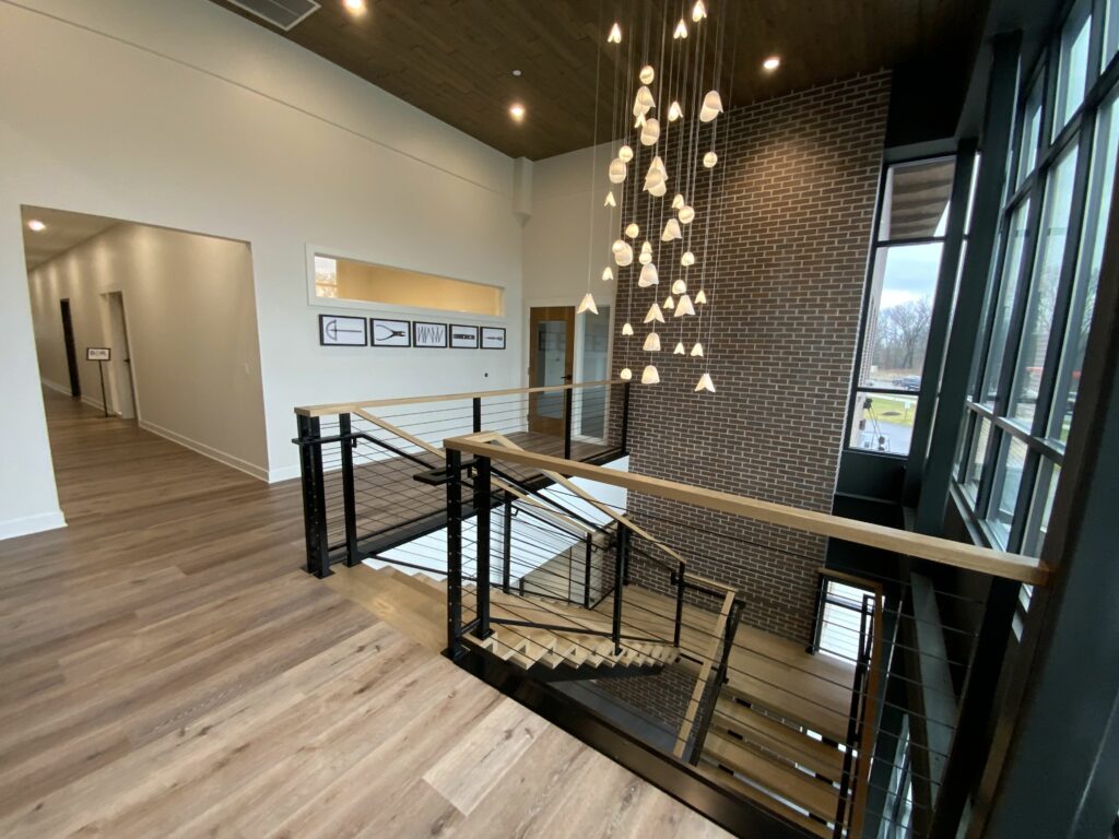 Upper level of commercial building with wood floors and stairs leading to lower level.