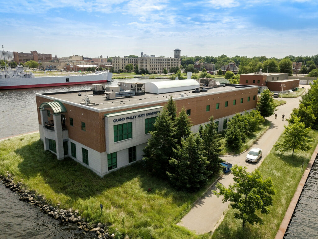 Aerial view of large, two-story brick building reading "Grand Valley State University" on its side.