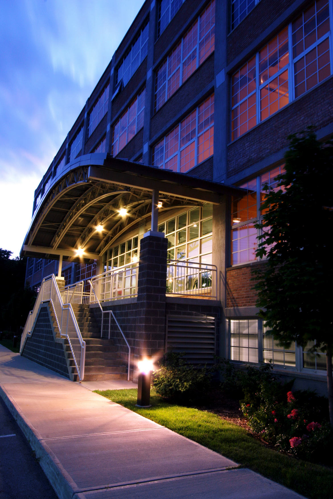 External view of entrance to a multi-family living complex at night. The stairs and the entrance are well lit.