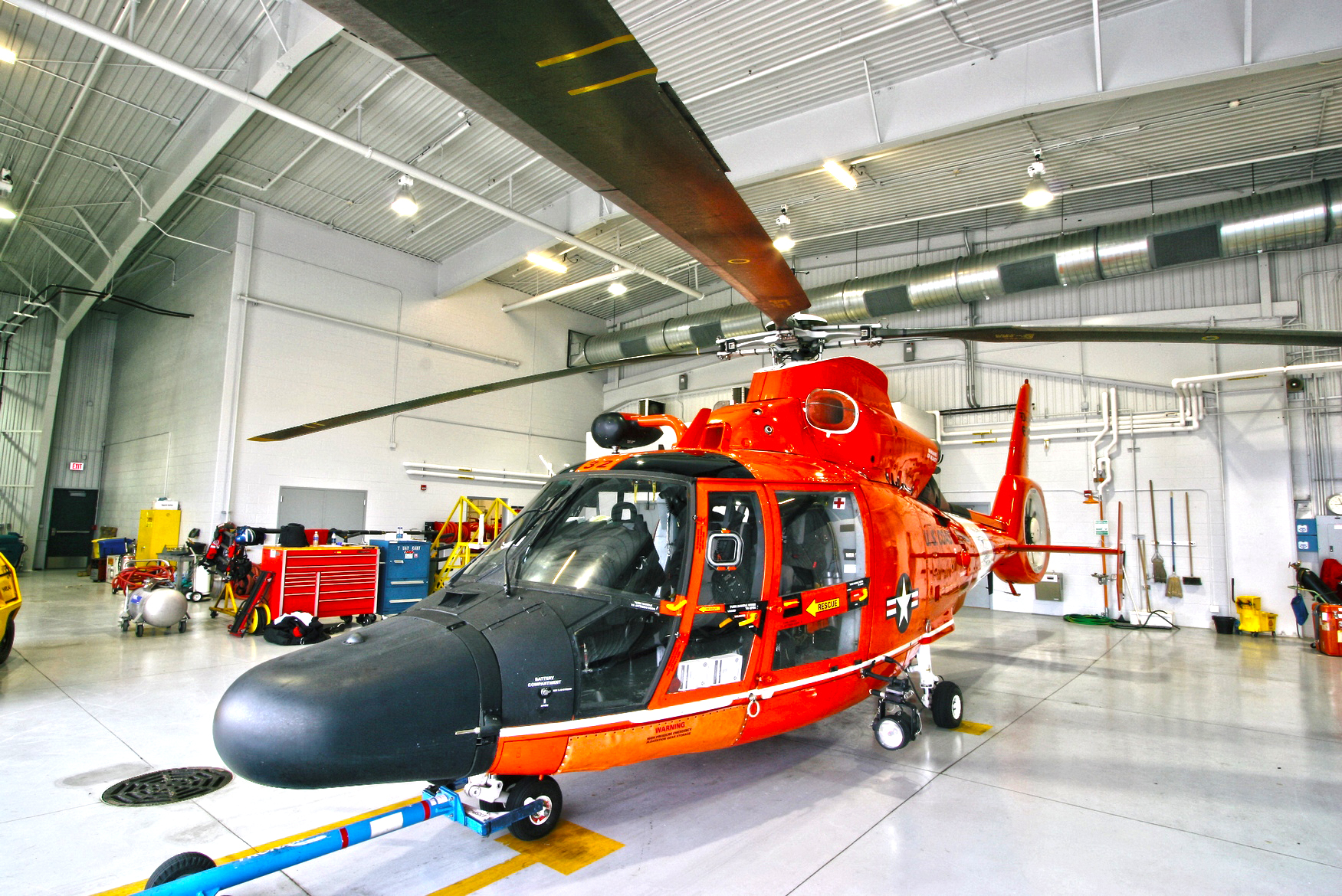 Interior of a hanger with a large red chopper in the foreground.