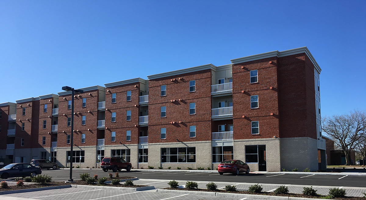 Four storied brick apartment complex with a large parking lot