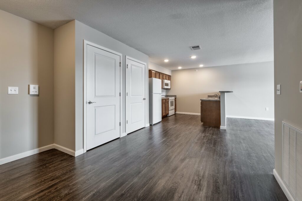 Open-concept of main living space and spacious kitchen, countertop, and fridge, with two closets in an Osborn Commons apartment unit.