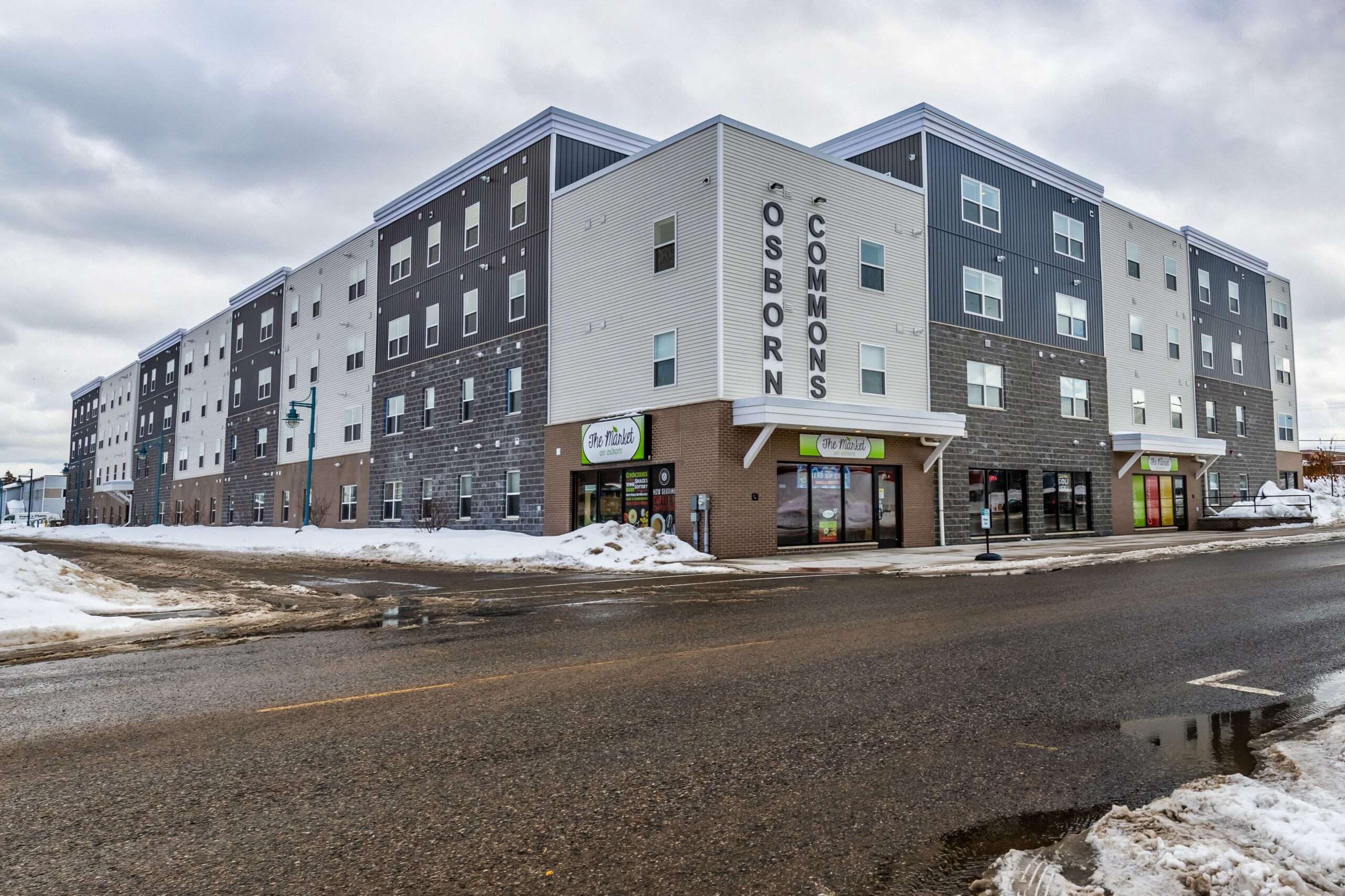 Angular view of the apartment building, Osborn Commons and building's market storefront on a winter day.